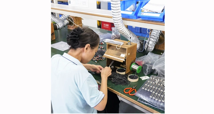 Technician assembling custom cables in a controlled, IATF 16949 compliant factory environment.